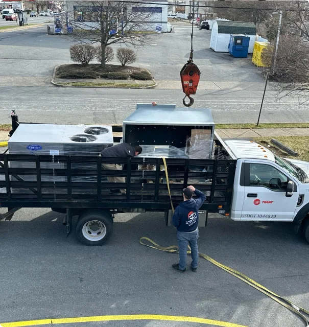 Crane lifting commercial RTU onto flatbed truck